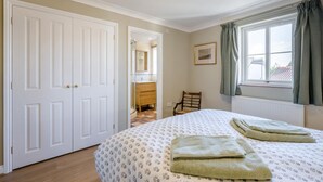 A bedroom with a bed, a chair, a window with curtains, a radiator, and a door. - 3 Bed in Holt (oc-s40247) (Holt)