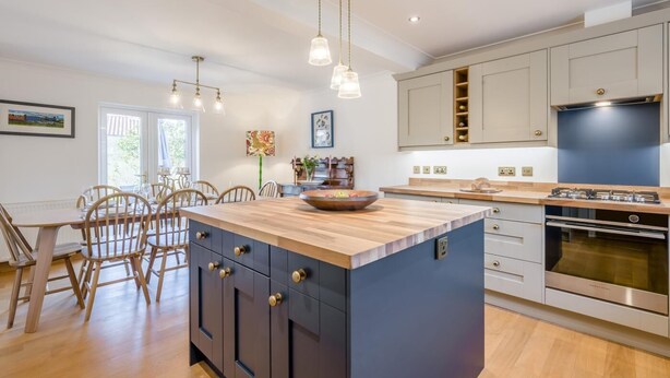 A modern kitchen with a central island, wooden chairs, pendant lighting, and a built-in oven. - 3 Bed in Holt (oc-s40247) (Holt)