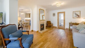 A living room with a fireplace, wooden flooring, a dining area with chairs, and a sofa. - 3 Bed in Holt (oc-s40247) (Holt)