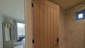 Un baño moderno con puerta de madera, pared de mármol y una ventana pequeña.