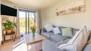 A modern living room with a grey sofa, a wooden coffee table, and a painting on the wall. - 2 Bed in Tyn-y-Groes (oc-w42450) (Ty'n-y-groes)
