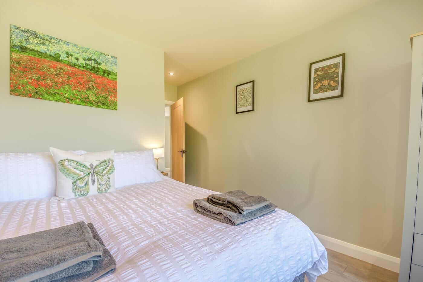 A bedroom with a bed, pillows, a painting, and a door.