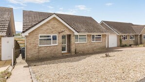 A row of single-story houses with tiled roofs, a gravel driveway, and a clear sky. - 3 Bed in Weymouth (oc-f41734) (Weymouth)