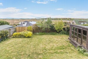 A residential backyard with a lawn, a wooden fence, and a house with a sloped roof.