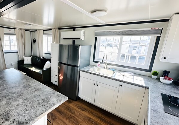Cocina moderna para vehículo recreativo, con refrigerador de acero inoxidable, un lavamanos y ventana con vistas a edificios.
