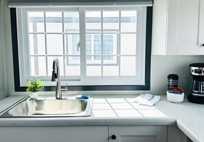 A modern kitchen with a large window, a stainless steel sink, and a coffee maker on the counter. - Two Private Bedrooms with Queen and Bunk Beds, Full Kitchen and In-Unit Laundry (Pecos)