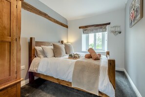 A bedroom with a wooden bed, white bedding, a window with a view, and a bedside table with a lamp. - 3 Bed in Papcastle (oc-c42478) (Papcastle)