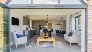 A modern living space with a dining area, kitchen, and seating. - 5 Bed in Bluntisham (oc-m40249) (Bluntisham)