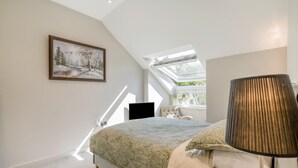 Et soveværelse med seng, et billede, en lampe og et vindue med udsigt.