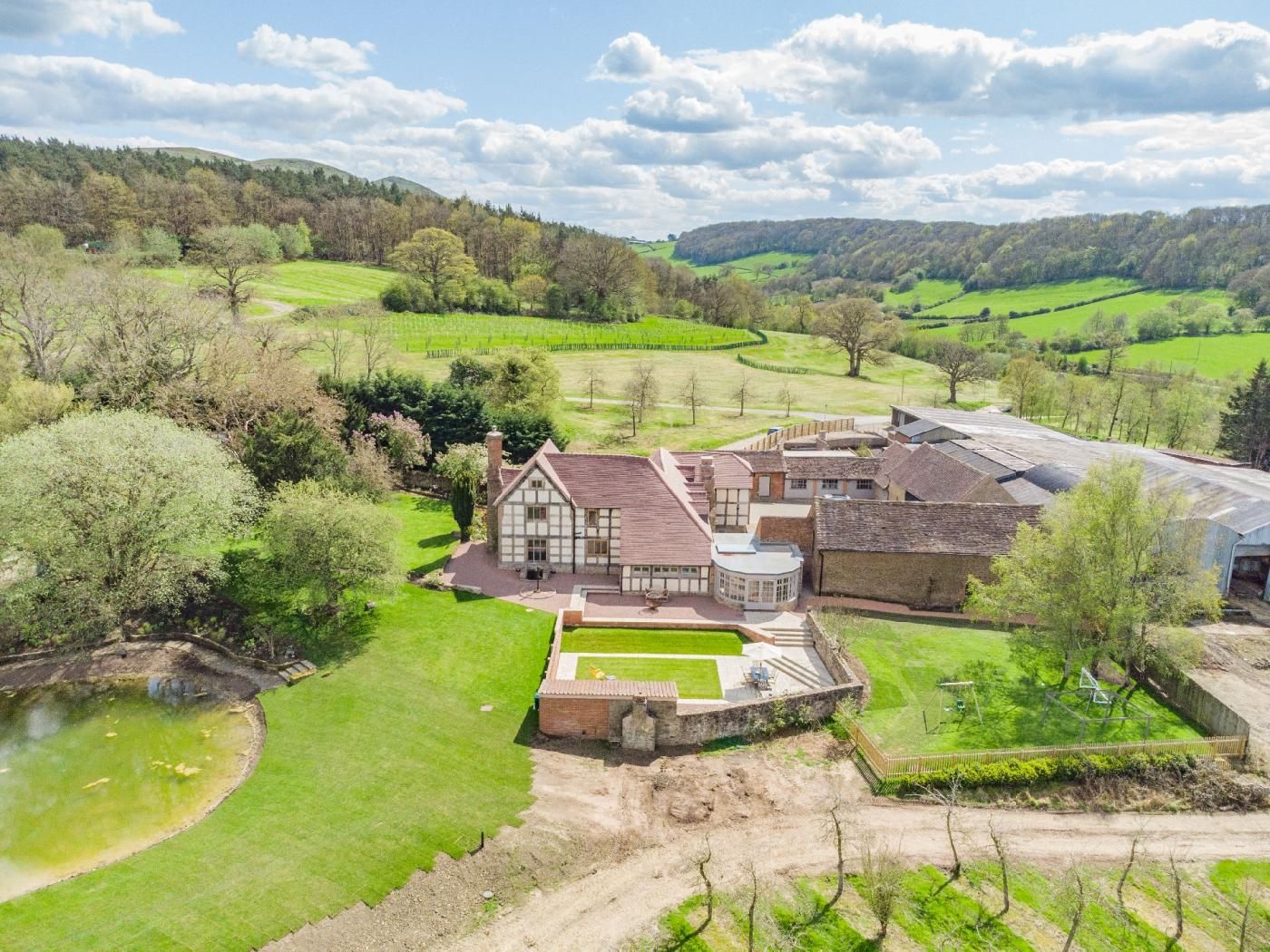 A large estate with multiple buildings, including a main house with a large garden and a pond.