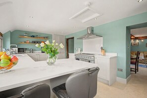 A modern kitchen with a central island, white cabinetry, and a stainless steel range hood. - 6 Bed in Storridge (oc-c39005) (Storridge)
