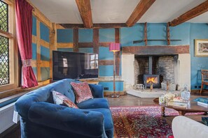 A cozy living room with a blue sofa, a fireplace, and a television. - 6 Bed in Storridge (oc-c39005) (Storridge)