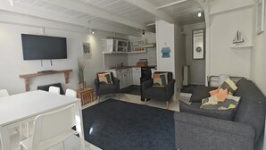 Ein modernes Wohnzimmer mit Essbereich, einer Küche und einem an der Wand befestigten Fernseher.