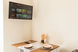 A hotel room with a TV mounted on the wall displaying a TV channel menu.