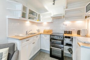 A compact kitchen with white cabinets, a sink, a toaster, and a stove. - 2 Bed in St. Ives (oc-b42453) (St Ives)
