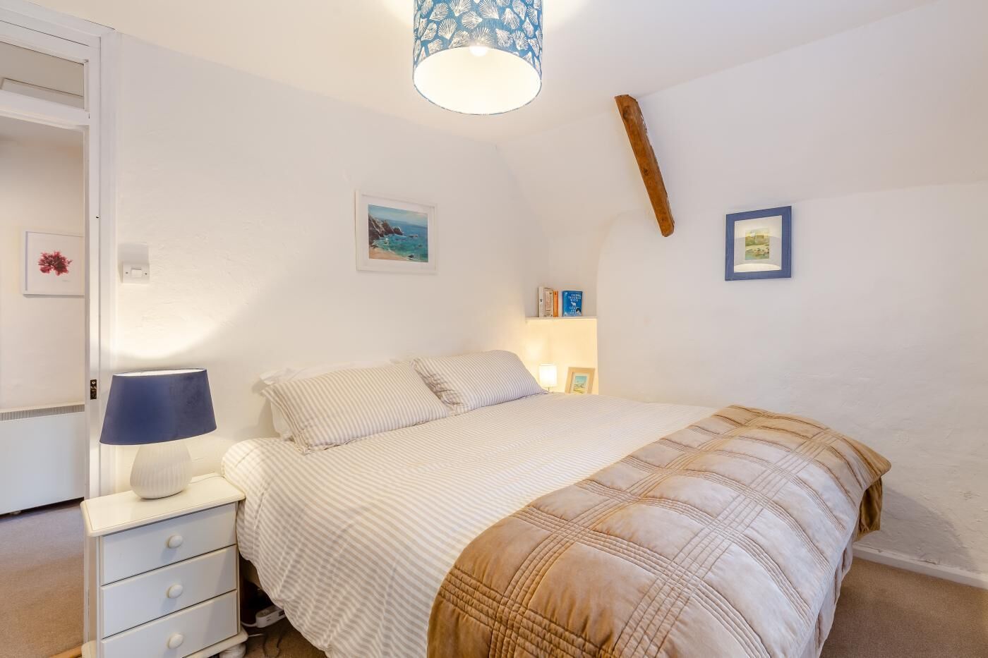 Une chambre à coucher avec un lit, une table de chevet avec une lampe, une commode et des étagères murales remplies de livres.