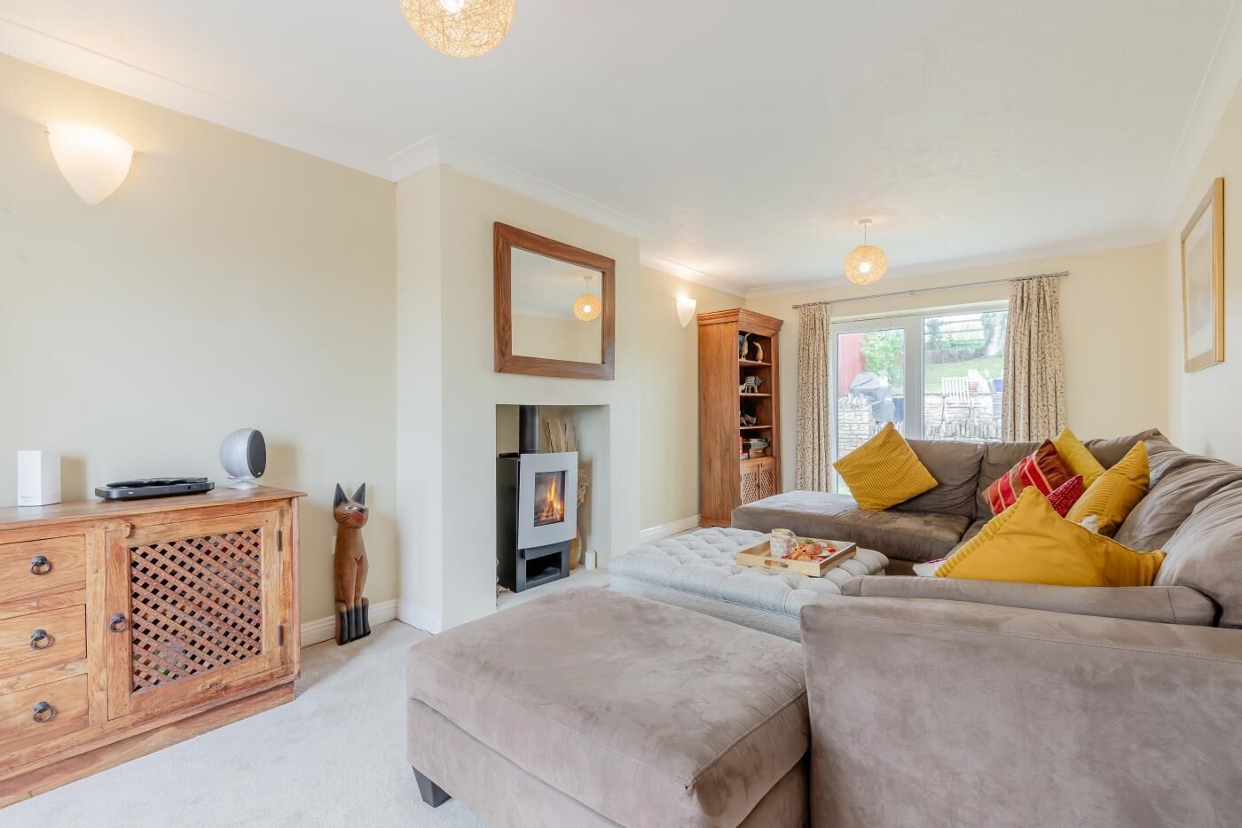 A cozy living room with a fireplace, a sofa set, and a wooden cabinet.
