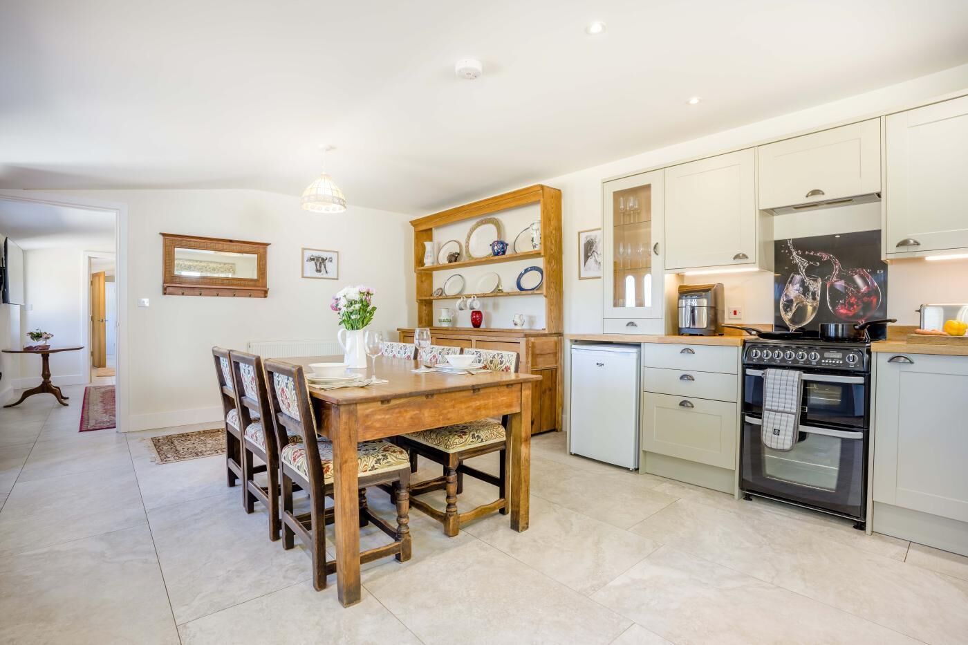 A compact kitchen with a dining area, featuring a wooden table, chairs, a refrigerator, and a stove.