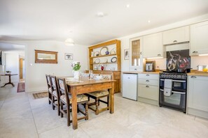 Eine kompakte Küche mit Essbereich, ausgestattet mit einem Holztisch, Stühlen, einem Kühlschrank und einem Herd.