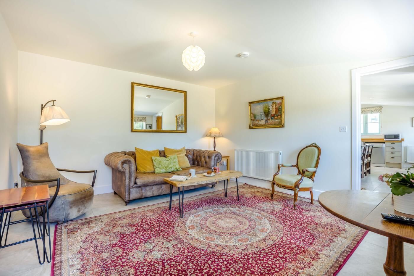 A living room with a sofa, armchairs, a coffee table, a rug, a mirror, and a painting.