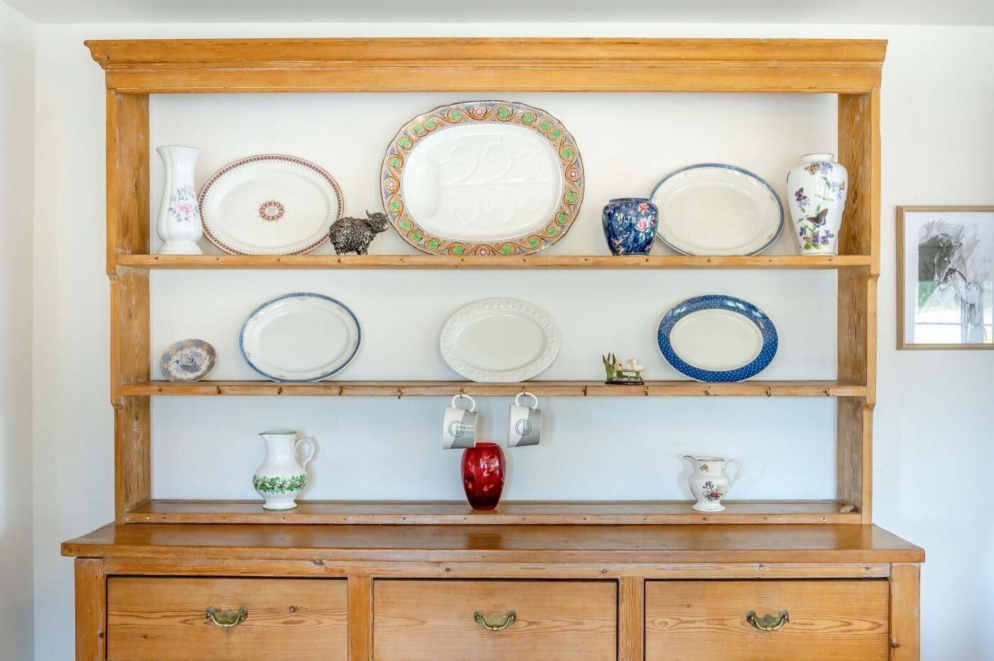 A wooden display shelf with various plates and vases.