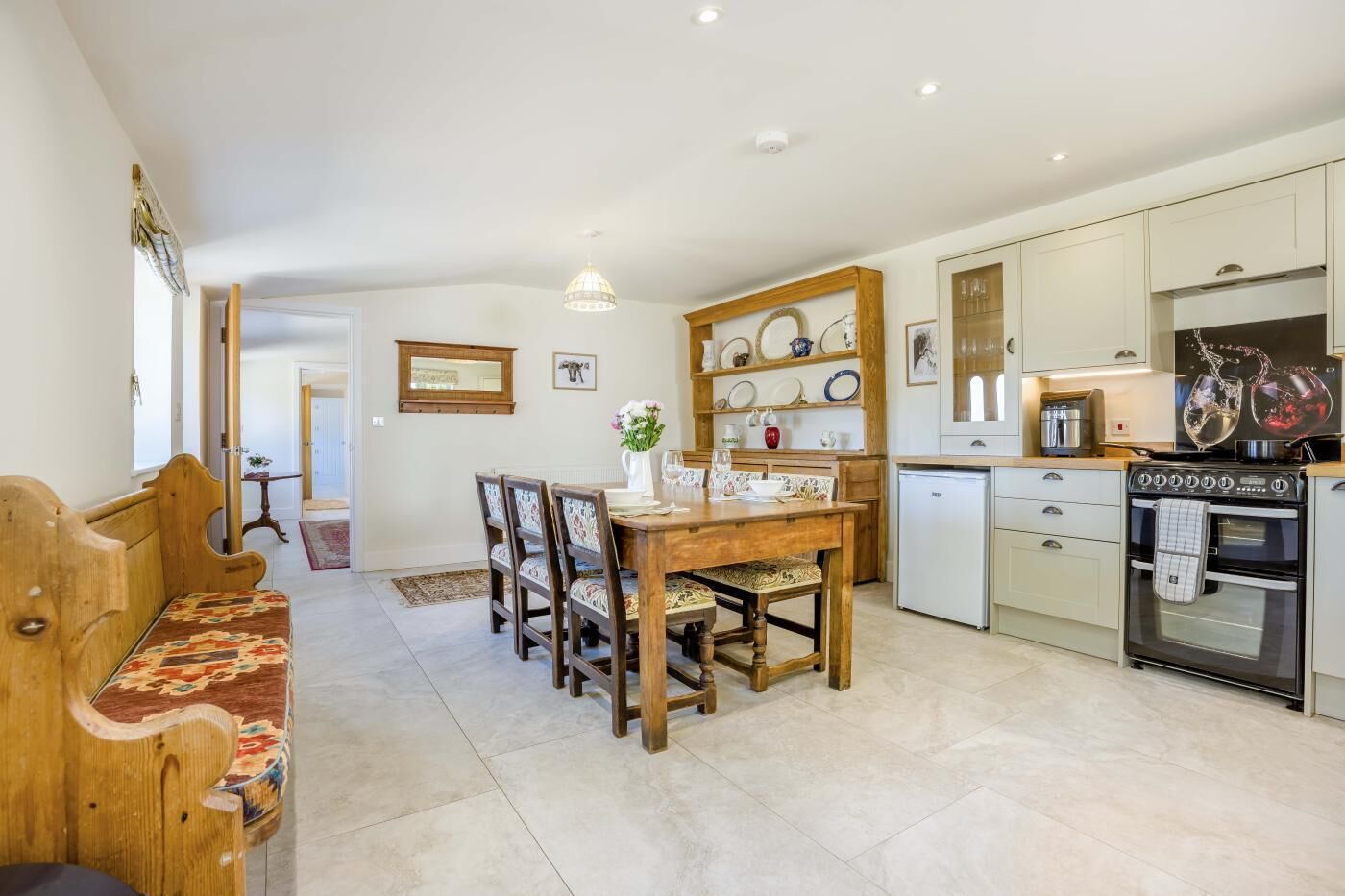 A modern kitchen with a dining area, featuring a wooden table, chairs, and a built-in oven.