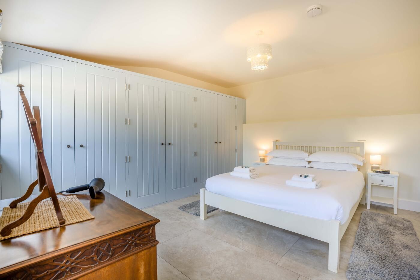 A bedroom with a bed, bedside tables, a wardrobe, and a wooden dresser.