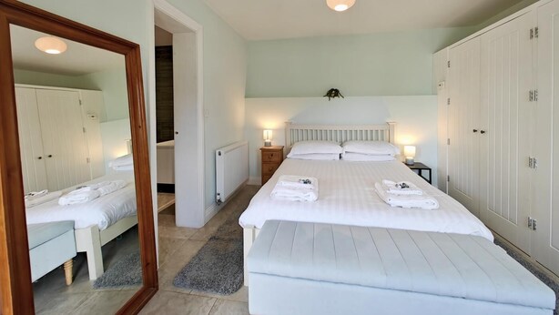 Une chambre à coucher avec un grand lit, des tables de chevet, un miroir et une armoire.