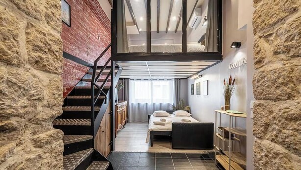 Un intérieur moderne avec un escalier, un lit et un mur en pierre.