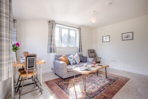 A living room with a sofa, coffee table, and a dining area with a table and chairs. - 1 Bed in Brockenhurst (oc-f40681) (Brockenhurst)