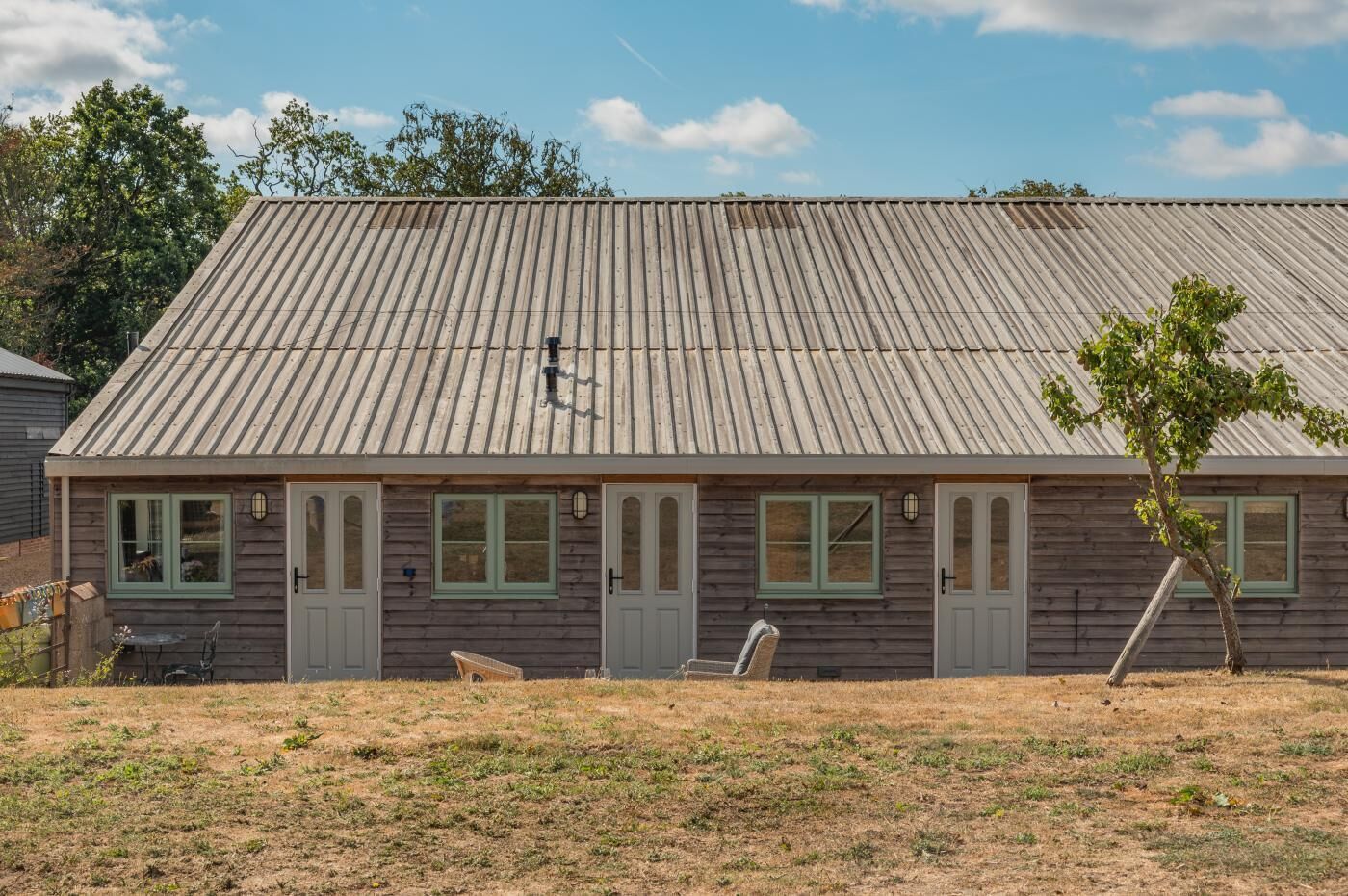 Un bâtiment d’un seul étage, doté d’un toit en tôle ondulée, d’un revêtement en bois et de nombreuses fenêtres.