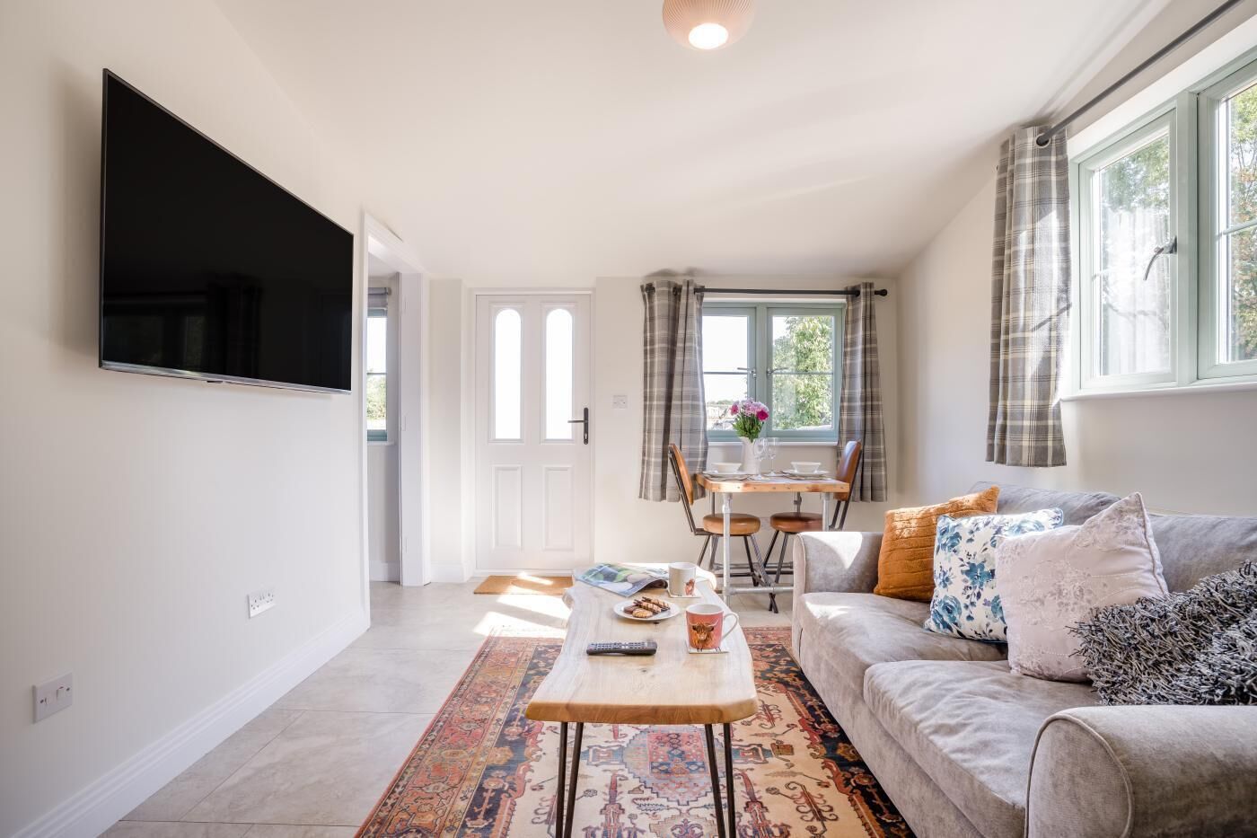 A living room with a flat-screen TV, a sofa, a coffee table, and a dining area with a table and chairs.
