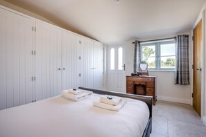 A bedroom with a bed, a dresser, and a window with curtains. - 1 Bed in Brockenhurst (oc-f40681) (Brockenhurst)