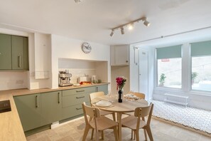 Una cocina moderna con comedor, un reloj y vistas por una ventana.