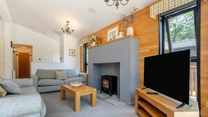 Ein Wohnzimmer mit Sofa, Kamin, Fernseher und einem Holz-TV-Möbel.