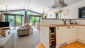 Ein geräumiger Wohnbereich mit einer Couch, einem Fernseher und einem Balkon mit großen Fenstern.
