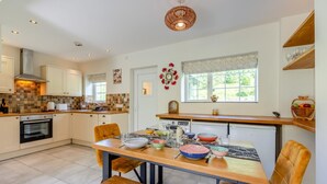 Une cuisine moderne avec un coin repas, comprenant un îlot central, des meubles en bois et une grande fenêtre offrant une belle vue.