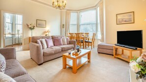 A living room with a sofa, coffee table, TV, dining table, and chairs. - 2 Bed in Scarborough (oc-g34248) (Scarborough)