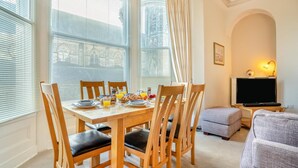 A dining area with a table set for breakfast, a television, and seating in a living room. - 2 Bed in Scarborough (oc-g34248) (Scarborough)