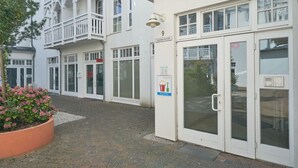 Ein Gebäude mit weißer Fassade, einem Schild mit der Nummer 9 und einem Glastür-Eingang.
