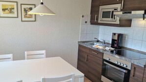 Eine Küche mit einem weißen Tisch, Stühlen, einer Mikrowelle und einem Backofen.