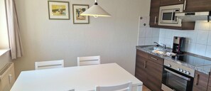 A kitchen with a white table, chairs, a microwave, and an oven. - Ostseeurlaub in Sellin mit Balkon (Sellin)