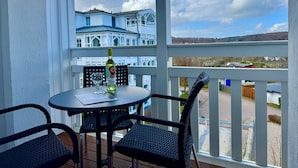 En balkon med et bord, stole, en vinflaske og et glas.