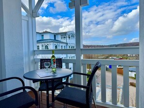 A balcony with a table, chairs, a bottle of wine, and a glass. - Gemutliche Ferienwohnung Nahe Ostseestrand in Sellin (Sellin)