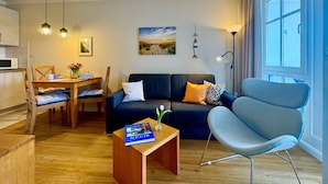 En moderne stue med sofa, lænestol, spisebord og en bog på et sofabord.