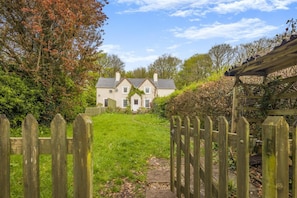 A traditional house with a front yard, a wooden fence, and a clear sky. - 3 Bed in Stackpole (oc-c41424) (Stackpole)