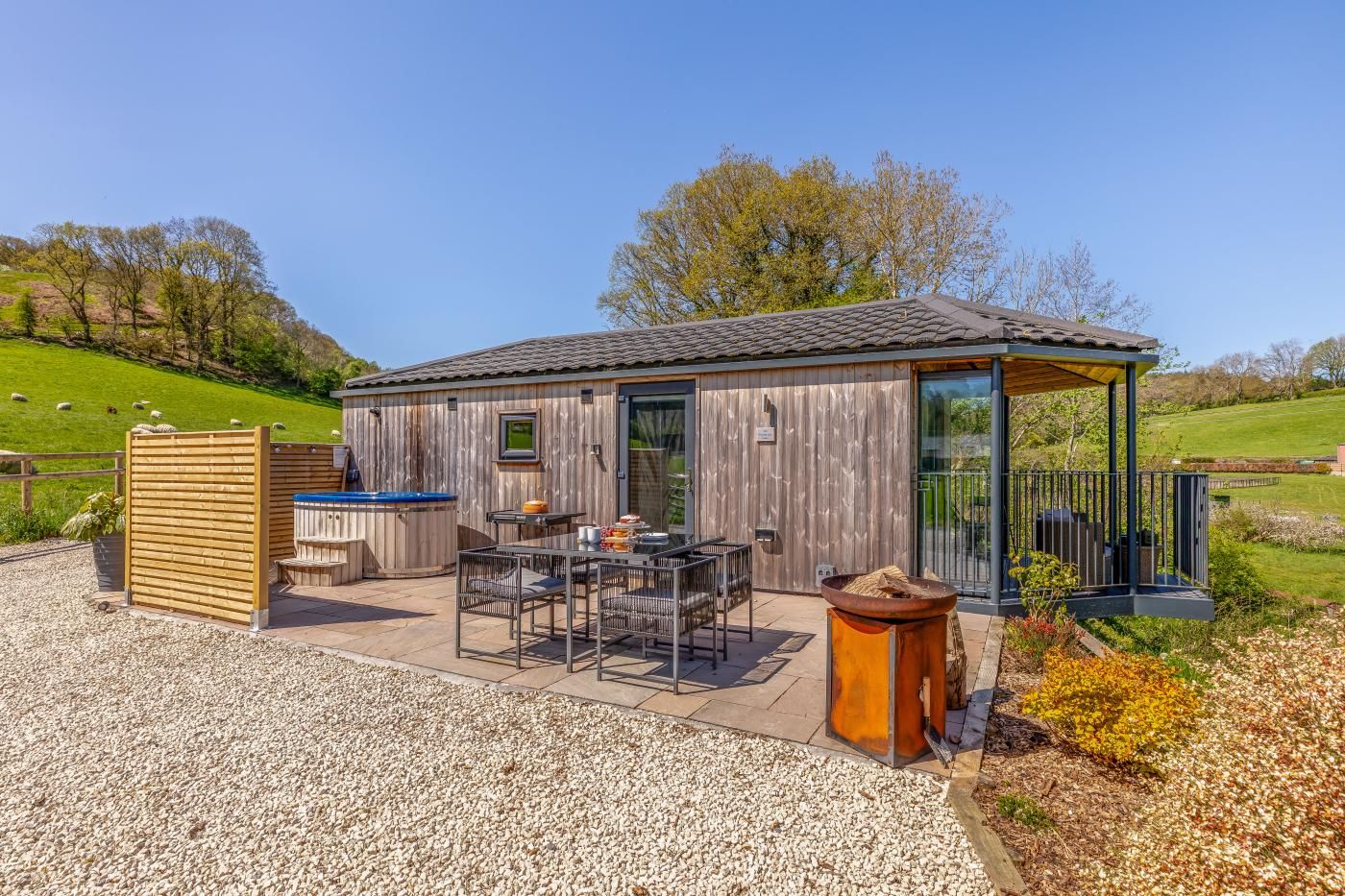 Une cabane en bois dotée d’une terrasse, d’un espace salon extérieur et d’un coin barbecue.
