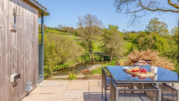 A wooden building with a table set for breakfast overlooking a river. - 1 Bed in Aberbechan (oc-t41392) (Newtown)