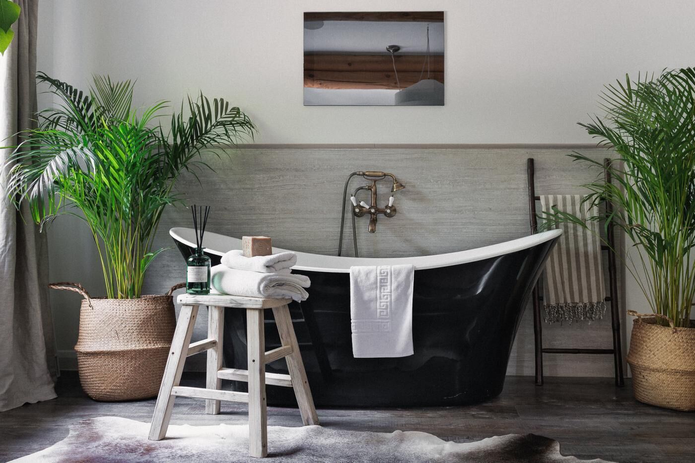 Une salle de bain avec une baignoire sur pieds, un tabouret en bois, un porte-serviettes et des plantes en pot.