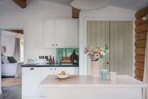 A modern kitchen with white cabinetry, a central island, and a vase of flowers.